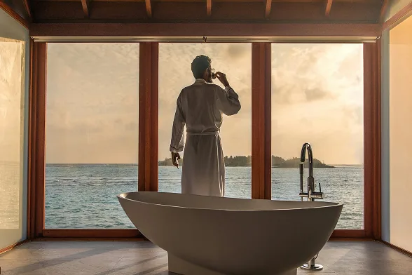 Guest at the window of an overwater villa at sunrise